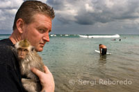 Un turista amb un mico a la platja de Kuta. Bali.