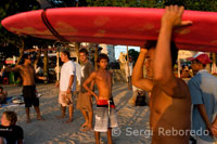 Un surfista recull la seva taula al vespre a la platja de Kuta. Bali.