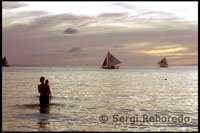 Una parella es banya al vespre a un paisatge més que romàntic. Bangka navegant. Capvespre a White beach. Boracay.