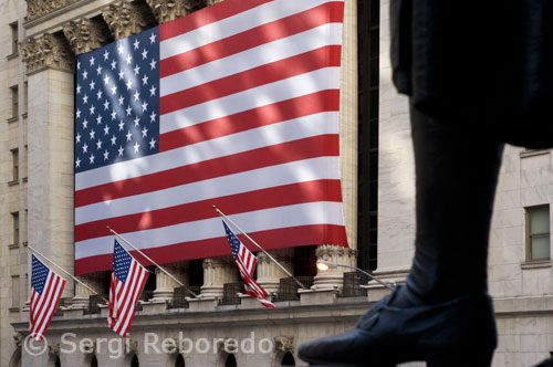 Edifici de la borsa novaiorquesa. New York Stock Exchange. 11 Wall St (està tancat al públic per motius de seguretat). L'edifici de la borsa, o anomenat també simplement Wall Street, s'ha convertit en el símbol mundial del capitalisme. Una bandera de grans dimensions oneja sobre la part de l'edifici que dóna al carrer Broad St, sota la qual desfilen els brokers vestits d'un costat a un altre del carrer. L'edifici és per si tot un espectacle l'edifici està situat a la cantonada de 5th Street amb Broadway al sud de Manhattan. Va ser construït i dissenyat amb un estil clàssic i elegant, alguns crítics fins i tot afirmen seu aire grec i imperial doncs 6 grans i amples columnes aparenten la força i el poder de tot el que s'hi decideix. Tota la zona del Wall Street actua com centre financer de la ciutat i en tota l'àrea hi ha molta arquitectura clàssica i gratacels envoltats finalment pel mar, que li confereix la particularitat de l'skyline novaiorquès. La Borsa de Nova York (New York Stock Exchange, NYSE, en anglès) és el major mercat de valors del món en volum monetari i el primer en nombre d'empreses adscrites. La seva massa en accions va ser superada per la del NASDAQ [1] durant els anys 90, però el capital de les companyies llistades en la NYSE és cinc vegades major que en el NASDAQ. La Borsa de Nova York té un volum anual de transaccions de 21 bilions de dòlars, incloent els 7,1 bilions de companyies no nord-americans.