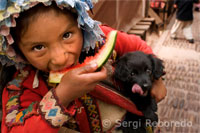 Una nena vestida amb un vestit tradicional menjant un tros de síndria a Pisac el diumenge, dia de mercat. Pisac. Valle Sagrado.