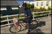 Las bicicletas y los coches de golf sustituyen a los coches en Hope Town. Local en bicicleta y al fondo casas lealistas – Hope Town – Elbow Cay – Abacos. Bahamas