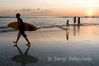 Un surfista recoge su tabla al atardecer en la playa de Kuta. Bali.