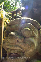 Los monos se divierten sobre las estatuas hinduistas de piedra de la Reserva Sagrada del Bosque de los Monos. Ubud. Bali.