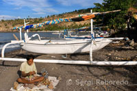 Un pescador junto a varias barcas de pesca en la playa de Amed, un pueblecito de pescadores del Este de Bali. 