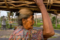 Una anciana recoge leña junto a la carretera que lleva al pueblo pesquero de Amed al Este de Bali.