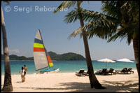 Los turistas toman el sol bajo las sombrillas. Barca para sailing en la isla de Pangulasian. Palawan.