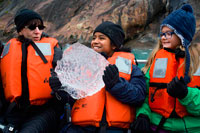 Juneau, Alaska, USA. Passengers of Safari Endeavour cruise playing with a big ice at Fords Terror, Endicott Arm, Tongass National Forest, Alaska, USA. The 49th State, the largest in the U.S., is perfect for cruisers, with numerous opportunities to appreciate its vast natural beauty. Sail along the Inside Passage to visit the immense ice formations of Glacier Bay and Icy Strait, as well popular ports such as Ketchikan, Skagway and Juneau