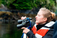 Juneau, Alaska, USA. Crew with binoculars on cruise ship Safari Endeavour at anchor at Fords Terror, Endicott Arm, Tongass National Forest, Juneau, Alaska, USA. Cliff-walled fjords sliced into the mountainous mainland are on tap today as you slowly slip into an area widely acclaimed as the most beautiful in Alaska. With more designated Wilderness Areas than any state in the nation, the finest include Endicott Arm and Ford’s Terror, a pristine tidal inlet and fjord. Explore this majestic fjord by kayak or skiff, a unique opportunity indeed.