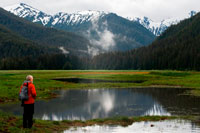 Juneau, Alaska, USA. Man doing hiking in Scenery Cove, Thomas Bay, Petersburg, Southeast Alaska. Thomas Bay is located in southeast Alaska. It lies northeast of Petersburg, Alaska and the Baird Glacier drains into the bay. Thomas Bay is also known as "The Bay of Death" due to a massive landslide in 1750. It also has gained the name of "Devil's Country" when in 1900 several people claimed to have seen devil creatures in the area. Thomas Bay is known for being rich in gold and quartz. The wildlife has moose, brown bears, black bears, squirrels, wolves, rabbits, and other common Alaskan creatures.