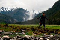 Juneau, Alaska, USA. Woman doing hiking in Scenery Cove, Thomas Bay, Petersburg, Southeast Alaska. Thomas Bay is located in southeast Alaska. It lies northeast of Petersburg, Alaska and the Baird Glacier drains into the bay. Thomas Bay is also known as "The Bay of Death" due to a massive landslide in 1750. It also has gained the name of "Devil's Country" when in 1900 several people claimed to have seen devil creatures in the area. Thomas Bay is known for being rich in gold and quartz. The wildlife has moose, brown bears, black bears, squirrels, wolves, rabbits, and other common Alaskan creatures. The land has been used for logging