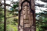 Juneau, Alaska, USA. Sign, The Raven clan territory, tree carving, Tlingit Indians, Juneau, Southeast Alaska. Mount Roberts. Trekking from the Mt Roberts Tramway, Juneau. Alaska. The top terminal of the tram is located on a tower and offers spectacular views of the City of Juneau and the Gastineau Channel, Douglas Island and the community of Douglas to the west, the Chilkat Mountain Range to the north, and Kupreanof Island to the South. The terminal platform is joined to the ridge of Mount Roberts by the Skybridge which leads to the summit facilities. The main building includes the Timberline Bar & Grill, the Chilkat Theater showing an informative film of the local Alaska Natives, and Raven Eagle Gifts. Located at the main building is the Stephen Jackson totem pole, a modern rendition of traditional Native themes.