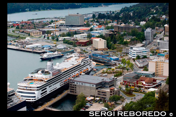 El centre de Juneau, ciutat. Alaska. EUA .. Dockeds vaixell Creuers entre muntanyes cobertes de neu i la Muntanya Roberts Tramvia al moll de Juneau, Alaska, EUA .. La terminal de creuers i la Muntanya Roberts Tramway, Alaska, dins el pas, Estats Units d'Amèrica. La ciutat i el municipi de Juneau és la capital d'Alaska. És un municipi unificat situat al canal anglès en el panhandle d'Alaska, i és la segona ciutat més gran d'Estats Units per àrea. Juneau és la capital d'Alaska des de 1906, quan el govern del que era llavors el Districte d'Alaska va ser traslladat de Sitka segons el dictat pel Congrés dels Estats Units en 1900. El municipi unificat l'1 de juliol de 1970, quan la ciutat de Juneau es va fusionar amb la ciutat de Douglas i els voltants Major Juneau Borough per formar el municipi l'autonomia actual. L'àrea de Juneau és més gran que la de Rhode Island i Delaware individualment i és gairebé tan gran com els dos estats combinats. Downtown Juneau es troba a la base de la Muntanya Juneau ia través del canal de l'illa de Douglas. A partir del cens de 2010, la ciutat i el municipi tenia una població de 31.275. Al juliol de 2013, l'estimació de la població de l'Oficina del Cens d'Estats Units era 32.660, pel que és la segona ciutat més poblada d'Alaska després d'Anchorage. (Fairbanks és però la segona àrea metropolitana més gran en l'estat, amb més de 97.000 residents.) Entre els mesos de maig i setembre, la població diària de Juneau poden augmentar en aproximadament 6.000 persones de visitar els vaixells de creuer.