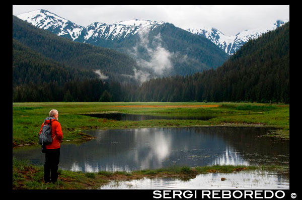 Man doing hiking in Scenery Cove, Thomas Bay, Petersburg, Southeast Alaska. Thomas Bay is located in southeast Alaska. It lies northeast of Petersburg, Alaska and the Baird Glacier drains into the bay. Thomas Bay is also known as "The Bay of Death" due to a massive landslide in 1750. It also has gained the name of "Devil's Country" when in 1900 several people claimed to have seen devil creatures in the area. Thomas Bay is known for being rich in gold and quartz. The wildlife has moose, brown bears, black bears, squirrels, wolves, rabbits, and other common Alaskan creatures. The land has been used for logging. Charlie claimed to have arrived in Thomas Bay, but couldn't find the half-moon shaped lake. Instead he spent some time off an 'S' shaped lake (actually called Ess Lake). He claimed that the surrounding area seemed oddly void of life. There were no squirrels, no birds, etc. Wanting to get his bearings after he found his large chunk of quartz, he climbed to the top of a ridge. From there he could spot Frederick Sound, Cape of the Straight Light, the point of Vanderput Spit (Point Vanderput), and Sukhoi Island from the mouth of Wrangell Narrows. Behind the ridge, Charlie finally spotted the half-moon shaped lake, which is where the Patterson Glacier turns into a lake that turns into Patterson River.