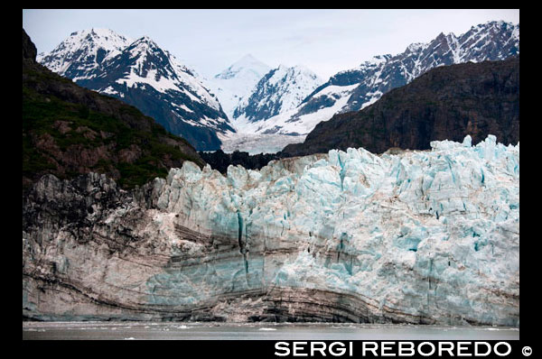 The Margerie Glacier and Mount Fairweather in Glacier Bay National Park Alaska USA. Tarr inlet in Glacier Bay National Park. Margerie Glacier is a 21-mile-long (34 km) tide water glacier in Glacier Bay in Alaska and is part of the Glacier Bay National Park and Preserve. It begins on the south slope of Mount Root, at the Alaska-Canada border in the Fairweather Range, and flows southeast and northeast to Tarr Inlet. It was named for the famed French geographer and geologist Emmanuel de Margerie (1862–1953), who visited the Glacier Bay in 1913. It is an integral part of the Glacier Bay, which was declared a National Monument on February 26, 1925, a National Park and Wild Life Preserve on December 2, 1980, a UNESCO declared World Biosphere Reserve in 1986 and a World Heritage Site in 1992. While most of the tidewater and terrestrial glaciers in the Park are stated to be thinning and receding over the last several decades, Margerie Glacier is said to be stable and Johns Hopkins Glacier is stated to be advancing, on the eastern face of the Fairweather Range. 