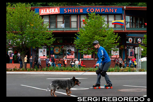 Downtown. Skating with a dog in the streets of Juneau. S Franklin street. Alaska Shirt Company. Alaska, USA.  The City and Borough of Juneau is the capital city of Alaska. It is a unified municipality located on the Gastineau Channel in the Alaskan panhandle, and is the second largest city in the United States by area. Juneau has been the capital of Alaska since 1906, when the government of what was then the District of Alaska was moved from Sitka as dictated by the U.S. Congress in 1900. The municipality unified on July 1, 1970, when the city of Juneau merged with the city of Douglas and the surrounding Greater Juneau Borough to form the current home rule municipality. The area of Juneau is larger than that of Rhode Island and Delaware individually and is almost as large as the two states combined. Downtown Juneau  is nestled at the base of Mount Juneau and across the channel from Douglas Island. As of the 2010 census, the City and Borough had a population of 31,275. In July 2013, the population estimate from the United States Census Bureau was 32,660, making it the second most populous city in Alaska after Anchorage.(Fairbanks is however the second-largest metropolitan area in the state, with more than 97,000 residents.) Between the months of May and September, Juneau's daily population can increase by roughly 6,000 people from visiting cruise ships.