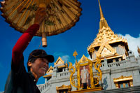 Bangkok. Venedor Umbrella. Façana d'un temple, Wat Traimit, Bangkok, Tailàndia. Wat Traimit a Bangkok. Temple de Buda d'or en el Barri Xino. Situat a l'extrem de Chinatown Yaowarat Road, prop de l'estació de tren Hualampong, Wat Traimit alberga més gran d'or massís del món de Buda assegut de mesurament de gairebé cinc metres d'altura i un pes de cinc tones i mitja. En el passat, els artesans fan a mà els Budes d'or i ells disfressats dels exèrcits invasors per una coberta d'estuc i guix. El Buda en Wat Traimit va ser descobert per accident quan cau accidentalment, ja que s'està movent, revelant, sota una coberta de guix, un bell or sòlid estil Sukhothai Buda. Els trossos de guix encara es mantenen en exhibició.