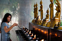 Bangkok. Mujer que ruega en Wat Patum Wanaram Tample. Bangkok. Wat Pathum Wanaram es un templo budista en Bangkok, Tailandia. Se encuentra ubicado en el distrito de Pathum Wan, entre los dos centros comerciales Siam Paragon y CentralWorld, y al cruzar la calle de la Plaza Siam. El templo fue fundado en 1857 por el rey Mongkut (Rama IV) como un lugar de culto cerca de su Sa Pathum Palace. En el momento de su fundación la zona era todavía sólo campos de arroz, sólo accesibles a través del Khlong Saen Saeb.