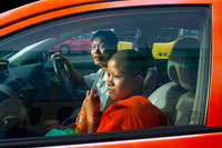 Bangkok. Monjo budista jove dins d'un taxi. La Sangha Mundial a Tailàndia consisteix en prop de 200.000 monjos i 85.000 novicis en la majoria de les èpoques de l'any. No obstant això, aquestes xifres augmenten durant el budista 'prestat' a 300.000 i 100.000 novicis. Els nois poden arribar a ser novicis en qualsevol edat, però l'home no pot arribar a ser un monjo fins que arriba a l'edat de vint anys. A continuació, pot seguir sent un monjo durant el temps que ho desitgi, encara que sigui per un sol dia. Tres mesos és més habitual, encara que alguns opten per romandre en monacat durant la resta de les seves vides. Tots els monjos han de seguir 227 preceptes estrictes o regles de conducta, molts dels quals es refereixen a les seves relacions amb els membres del sexe oposat.