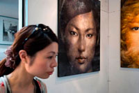 Bangkok. Woman in a art gallery in Chatuchak Weekend Market or Jatujak Market; is one of the world's largest weekend markets covers area of 70 rai (27 Acres) altogether divided into 27 Sections, contains more than 15,000 booths selling goods from every part of Thailand. Chatuchak Weekend Market,is very popular shopping centre to Thais and has become a popular place to tourists and foreigners who stay in Bangkok, has over 200,000 visitors each day(SAT-SUN) 30% is foreign.