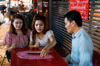 Bangkok. Lector de Tarot. endeví a Bangkok Tailàndia donar una lectura a la carretera Yaowarat a la nit al cèntric barri de Chinatown de Bangkok, Tailàndia. Yaowarat i Phahurat és multicultural barri de Bangkok, situada a l'oest de Silom i sud-est de Rattanakosin. Yaowarat Road és la llar de la comunitat xinesa gran de Bangkok, mentre que els d'ètnia índia s'han congregat al voltant Phahurat Road. Durant el dia, Yaowarat no es veu molt diferent de qualsevol altra part de Bangkok, encara que el barri se sent com un gran mercat del carrer i hi ha algunes joies ocultes esperant a ser explorat. Però a la nit, els rètols de neó resplendents amb caràcters xinesos estan encesos i les multituds dels restaurants es deixen caure pels carrers, convertint la zona en una miniatura de Hong Kong (menys els gratacels).