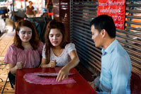 Bangkok. Tarot reader. fortune teller in Bangkok Thailand giving a reading in Yaowarat road at night in central Chinatown district of Bangkok Thailand. Yaowarat and Phahurat is Bangkok's multicultural district, located west of Silom and southeast of Rattanakosin. Yaowarat Road is the home of Bangkok's sizable Chinese community, while those of Indian ethnicity have congregated around Phahurat Road. By day, Yaowarat doesn't look that much different from any other part of Bangkok, though the neighbourhood feels like a big street market and there are some hidden gems waiting to be explored. But at night, the neon signs blazing with Chinese characters are turned on and crowds from the restaurants spill out onto the streets, turning the area into a miniature Hong Kong (minus the skyscrapers).