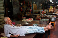 Bangkok. Elder mentir y dormir en un tatami en un alimento Parada del mercado y la calle está preparando en el barrio chino de Bangkok, Tailandia. Yaowarat, el barrio chino de Bangkok, es el más famoso destino comida de la calle en el mundo y el distrito de comedor favorito local. En esta aventura la noche temprano, traemos a descubrir los sabores sofisticados de comunidad de 200 años de Bangkok que es rica en tradición entre Tailandia y China y la comida deliciosa. Durante el recorrido usted tendrá que caminar para explorar y degustar la cocina local de 7 restaurantes famosos, varió de vendedores ambulantes de alimentos a renombrados comensales entre Tailandia y China.