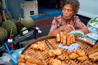 Bangkok. Mujer que vende rollos pring y frutas durian. Chinatown de Bangkok, Tailandia. Parada del mercado y la comida de la calle están preparando en el barrio chino de Bangkok, Tailandia. Yaowarat, el barrio chino de Bangkok, es el más famoso destino comida de la calle en el mundo y el distrito de comedor favorito local. En esta aventura la noche temprano, traemos a descubrir los sabores sofisticados de comunidad de 200 años de Bangkok que es rica en tradición entre Tailandia y China y la comida deliciosa. Durante el recorrido usted tendrá que caminar para explorar y degustar la cocina local de 7 restaurantes famosos, varió de vendedores ambulantes de alimentos a renombrados comensales entre Tailandia y China.