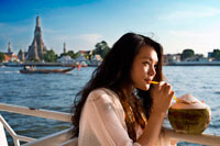 Bangkok. Buena chica romántica en un barco cerca de Templo Wat Arun y del río Chao Praya. Beber una coconout. Chao Phraya barco turístico. El BTS Skytrain se da la mano con el proveedor de Bangkok mayor público de agua de transporte, el Chao Phraya Barco expreso Co., Ltd. (establecido hace 38 años) para introducir un nuevo servicio de transporte de agua "El Chao Phraya barco turístico". Este servicio ofrece a los turistas la oportunidad de ver Bangkok desde una perspectiva totalmente nueva, en un solo día, el turista puede viajar fácilmente en los barcos de alta cantidad de muelle a muelle sin preocuparse por la compra de billetes de barco o perderse.