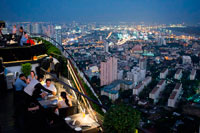 Bangkok. Landscape, views. Banyan Tree Rooftop Vertigo & Moon Bar, Restaurant, , Bangkok , Thailand. View of the city, Vertigo Bar and Restaurant, roof of the Banyan Tree Hotel, at dusk Bangkok, Thailand, Asia. Reaching for the clouds at Vertigo and Moon Bar on the 61st floor of the Banyan Tree hotel is one of the best ways to end a long day in Bangkok. There is no lack of rooftop bars in town but Vertigo has always been amongst the favourites. With an unusual narrow and elongated shape, the entire top of the building is occupied by both the bar and the restaurant and gives the unusual impression of being aboard a spaceship in the sky. Located on Sathorn road, a very large busy avenue peppered with tall glass and metal skyscrapers and not far from the Lumpini park and Silom area, Banyan Tree is a name often associated with luxury. 