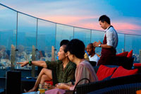 Bangkok. Xarxa Sky Bar al terrat. Bangkok. Tailàndia. A la planta superior de l'Centara Grand gratacels al centre de la ciutat. La vista Chinatown, més el Gran Palau i temples de l'illa de Rattanakosin. Xarxa Sky és un dels nous bars del terrat i restaurant a Bangkok. Si bé no ofereix colpejar la vora del riu o vistes copes dels arbres que altres bars del terrat gaudeixen, té bastant impressionants vistes panoràmiques de 360 graus del seu pis 55, un dels llocs més convenients de la ciutat. Si vostè visita Bangkok, és probable que el resultat final serà anar de compres a la zona de Siam, on es troben els més grans i moderns centres comercials, com el llegendari Siam Paragon, MBK i el CentralWorld recentment reconstruït.