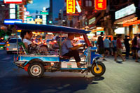 Bangkok. Tuk tuk in the street. View down Thanon Yaowarat road at night in central Chinatown district of Bangkok Thailand. Yaowarat and Phahurat is Bangkok's multicultural district, located west of Silom and southeast of Rattanakosin. Yaowarat Road is the home of Bangkok's sizable Chinese community, while those of Indian ethnicity have congregated around Phahurat Road. By day, Yaowarat doesn't look that much different from any other part of Bangkok, though the neighbourhood feels like a big street market and there are some hidden gems waiting to be explored. But at night, the neon signs blazing with Chinese characters are turned on and crowds from the restaurants spill out onto the streets, turning the area into a miniature Hong Kong (minus the skyscrapers). 