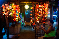 Bangkok. Color lamps seller in khao san road. Bangkok. Khaosan Road or Khao San Road is a short street in central Bangkok, Thailand. It is in the Banglamphu area of (Phra Nakhon district) about 1 kilometre (0.62 mi) north of the Grand Palace and Wat Phra Kaew. "Khaosan" translates as "milled rice", a reminder that in former times the street was a major Bangkok rice market. In the last 20 years, however, Khaosan Road has developed into a world famous "backpacker ghetto". It offers cheap accommodation, ranging from "mattress in a box" style hotels to reasonably priced 3-star hotels. In an essay on the backpacker culture of Khaosan Road, Susan Orlean called it "the place to disappear".