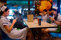 Bangkok. Trabajadores de la clínica niñas bonitas atractivas vestidas como enfermeras comiendo en un Kentucky Fried Chicken. Bangkok. Tailandia.