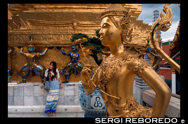 Grand Palace Wat Phra Kaeo Gold Statue Apsonsi and tourists. Bangkok Thailand. Wat Phra Kaew, Grand Palace, Statues in Wat Phra Kaew. Grand Palace and Emerald Buddha temple Wat Phra Kaeo. The Grand Palace RTGS: Phra Borom Maha Ratcha Wang is a complex of buildings at the heart of Bangkok, Thailand. The palace has been the official residence of the Kings of Siam (and later Thailand) since 1782. The king, his court and his royal government were based on the grounds of the palace until 1925. The present monarch, King Bhumibol Adulyadej (Rama IX), currently resides at Chitralada Palace, but the Grand Palace is still used for official events. Several royal ceremonies and state functions are held within the walls of the palace every year. The palace is one of the most popular tourist attractions in Thailand. The Outer Court or Khet Phra Racha Than Chan Na of the Grand Palace is situated to the northwest of the palace (the northeast being occupied by the Temple of the Emerald Buddha). Entering through the main Visetchaisri Gate, the Temple of the Emerald Buddha is located to the left, with many public buildings located to the right. The Temple of the Emerald Buddha or Wat Phra Kaew known formally as Wat Phra Si Rattana Satsadaram, is a royal chapel situated within the walls of the palace. Incorrectly referred to as a Buddhist temple, it is in fact a chapel; it has all the features of a temple except for living quarters for monks. Built in 1783, the temple was constructed in accordance with ancient tradition dating back to Wat Mahathat, a royal chapel within the grounds of the royal palace at Sukhothai, and Wat Phra Sri Sanpetch at Ayutthaya. The famed Emerald Buddha is kept within the grounds of the temple.