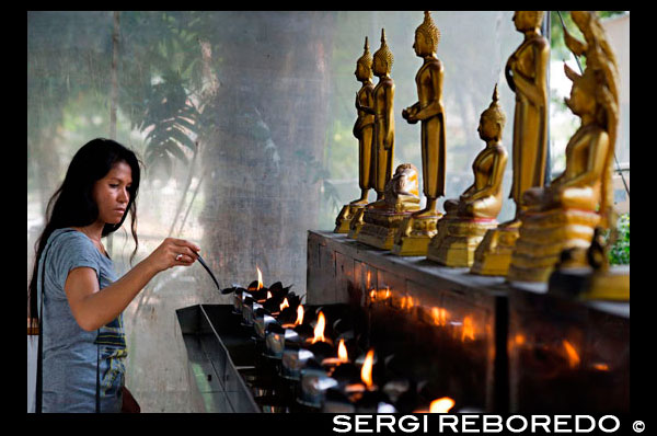 Woman praying in Wat Patum Wanaram Tample. Bangkok. Wat Pathum Wanaram is a Buddhist temple in Bangkok, Thailand. It is located in the district Pathum Wan, between the two shopping malls Siam Paragon and CentralWorld, and across the street of Siam Square. The temple was founded in 1857 by King Mongkut (Rama IV) as a place of worship near his Sa Pathum Palace. At the time of its founding the area was still only rice fields, only accessible via the Khlong Saen Saeb. The temple is a third class royal temple of the Thammayut Nikaya order. The full name of the temple is Wat Pathum Wanaram Ratcha Wora Viharn The ashes of Thai Royal Family members in the line of Prince Mahidol Adulyadej are interred at the temple. Among the various buildings of the temple is a sala partially reconstructed from the crematorium of the late Princess Mother of Thailand. The crematorium was a rare example of ancient craftsmanship featuring ornate stencils and lacquered sculptures. Known in Thai as phra men, it represents Mount Meru, the heavenly abode of the gods.