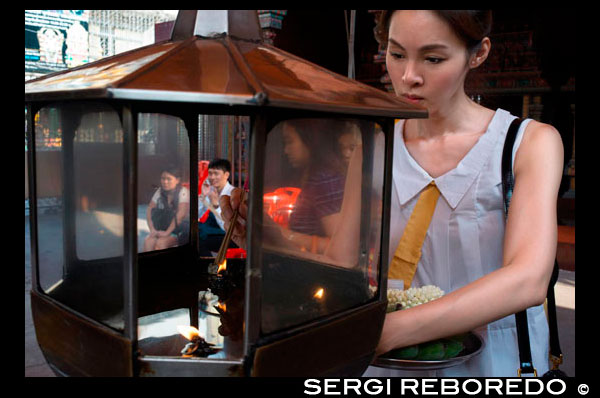 Woman praying in Erawan Shrine. Bangkok. Thailand. Erawan Shrine in Bangkok is Brahman, not strictly Buddhist. And yet, this famous shrine attracts more visitors than many of the city's temples. It was erected during the mid 1950s, after the Thai government had decided to build the luxury Erawan Hotel on this location. However, the first stages of the construction were beset with so many problems that superstitious labourers refused to continue unless the land spirits were appeased. After consultations with astrologers, the erection of a shrine to honour the four-faced Brahma God, Than Tao Mahaprom, was considered to be an auspicious solution. A magnificent image of the Brahma God was especially cast and gilded, and The Erawan Hotel opened to acclaims and worldwide fame for three decades. Towards the end, the property could not compete with more modern facilities, and was replaced by the privately owned Grand Hyatt Erawan Bangkok in 1991. As the shrine was originally constructed to grace the old Erawan Hotel, the location became known as the Erawan Shrine. Than Tao Mahaprom is a Brahma god, full of kindness, mercy, sympathy and impartiality. These four virtues are represented by his four faces, each radiating serene grace. Since Buddhism in Thailand has always been influenced by the Brahma beliefs, he made an immediate impact. Nowadays, as has been the case for years, unending streams of people pay respects from early morning till late at night. Thais, and even foreign visitors, make ceremonial offerings from floral garlands, fruits to teakwood elephants in the hope that their wishes will be fulfilled. Judging from the flowing multitude of believers, for many those wishes were indeed granted.