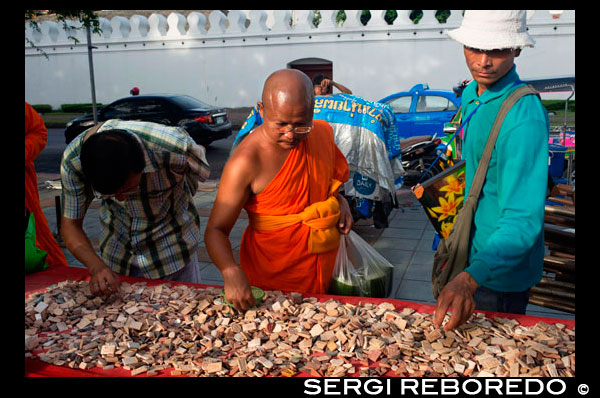 Buddhist monk and another people buying a amulets, periapts. Amulet market. Bangkok. Buddhist monks seen looking at protective amulets at a Bangkok market. Thailand Amulets Online Store – Authentic Sacred Thai Buddhist Amulets – Ancient and Modern. Thai Buddhist and Magical amulets for Riches, Luck, Health, Love and Happiness. Amulets by Thailand’s great ‘Gaeji Ajarn’ Guru Master Monks, Lay Masters, Necromancers and Hermit Sorcerors. All of our Thai Buddhist Amulets are guaranteed Authentic, & from Thailand. Buddha Image, Loi Ongk statuettes, Buddhist Monk Coin Amulets, Takrut Charms, Nam Man Prai Oils, Mai Kroo Wands, Mitmor Ritual Knife, Lek Lai Kaya Siddhi Elemental Substance, Kumarn Tong, Gambling Amulets, Mae Nang Prai, Muan Sarn Sacred Powder Amulets, Palad Khik, Animist Charms, Necromantic Amulets, Buddhist, Animist, Brahman and Necromantic Amulets.  All of our Thai Buddha amulets are 100% authentic materials found in Buddhist temples in Thailand. We have no jewelers' amulets, because we do not buy from Thai jewelry shops like many amulet stores online do. We buy only from a small group of Thai temples that we especially like. Our collection of Theravada Buddha amulets is unique and comparable with any other site online you can find - except  - ours are all genuine amulets. We live here. We buy only from the temples directly - with no middle man. We give 10% of what we made back to the temple we bought from. The temple benefits twice then - initially when we buy the Buddha amulets, and again when we sell them. 