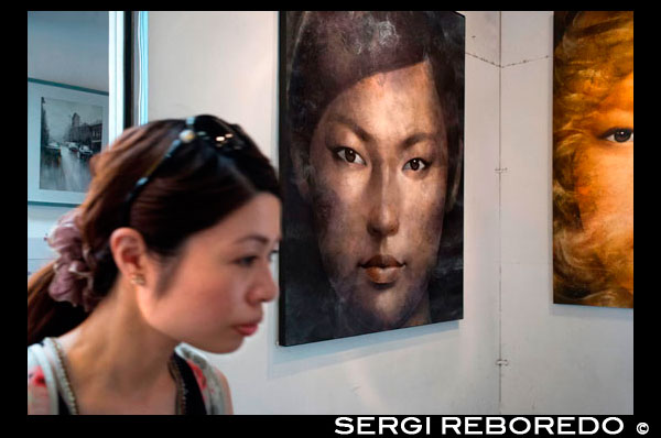 Woman in a art gallery in Chatuchak Weekend Market or Jatujak Market; is one of the world's largest weekend markets covers area of 70 rai (27 Acres) altogether divided into 27 Sections, contains more than 15,000 booths selling goods from every part of Thailand. Chatuchak Weekend Market,is very popular shopping centre to Thais and has become a popular place to tourists and foreigners who stay in Bangkok, has over 200,000 visitors each day(SAT-SUN) 30% is foreign. There are almost everything can be found here at a bargaining local price (not a tourist price), and most vendors actually come from local factories, like antique wood carving, clay handicrafts, local souvenirs from every parts of Thailand, Buddhist amulets, wooden funitures, hand made decorated flowers, plant, ceramic wares, dools, Thai Bejarong, Chinese wares, graden decorated plants, stones, trendy fashions, silk, hill-tribe outfits, fluffy dogs and more miscellaneous, etc.