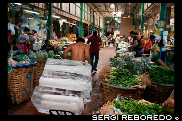 Ice Seller. Agricultural Product Central Market Wang Burapha Phirom. Ban Mo street. Bangkok. Asia. Pak Khlong Talat (Flower Market). Bangkok.  Pak Khlong Talat is a market in Bangkok well known for its wholesale flowers. However, little is written about the volumes of fresh fruits and vegetables on which Pak Khlong Talat was once established during its reign as Bangkok’s largest bulk produce market. During an early Sunday morning visit, we explored one of the most impressive displays of fresh produce that we’ve ever come across.  The Pak Khlong Talat is a wholesale produce market, evident by its massive displays of fruit and vegetables. There are woven baskets the size of wine barrels that are home to shredded ginger, chilies, and oranges; bundles of lemongrass and asparagus barely able to fit under one’s arm; truckloads of cabbages, onions, and garlic. The sheer volume of produce is incredible! There is a lot of movement with the produce itself. Hand carts, stacked six or eight feet tall with bags and baskets, can be regularly spotted being wheeled through the narrow streets. These goods are on their way to be delivered to other markets or to restaurants. Beautiful and rugged, huge displays of fresh fruit and vegetables stretch on and on throughout the market. Nearly perfect fruit are laid out in repeating rows for potential buyers. The variety is never ending. Some displays weren’t the table set-ups we usually see. The market seems to spill from two- and three-story shop-houses embedded along the narrow market streets. Garage entranceways serve as areas to temporarily stage stacks of fresh produce. What makes the Pak Khlong Talat market memorable and different from other markets we’ve visited is the quiet calmness it evokes. It is quite large (several sois wide) and because it is in Bangkok, we expected it to be packed with people, both Thais and foreign tourists alike.