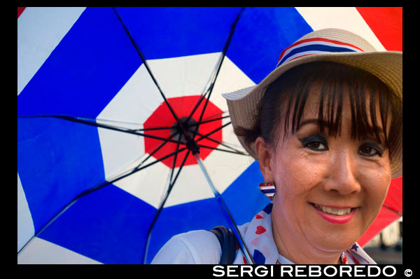 Transexual with an umbrella. Flag of Thailand. Bangkok. IT IS, one imagines, every sex-tourist's nightmare: the go-go bar, the tuk-tuk, the hotel room and then...the discovery that there is rather more to the lovely lady than had been bargained for. Thailand's ladyboys have struck again.  Richard Totman, a theatre director-cum-psychologist, has taken the trouble to get to know several kathoey over a period of years, and his book is a gentle and fascinating account of their lives. Kathoey, he maintains, genuinely are neither male nor female, but something in between that he calls a “third sex”, though in truth his belief is that sex is really more of a continuum.  Their origins are traced far back in Buddhist, and even into animist, scripture, and there is a canter through some of the biology—but Mr Totman's studies do not reveal any genetic or biological difference between kathoey and normal males. Most of the kathoey he interviewed, however, say that they have felt like women trapped in men's bodies from an early age. Where Thailand differs from most countries in the West is that such people have historically been accepted in a way which Europeans generally would find impossible.