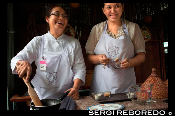 Amita Thai Cooking School. Bangkok. Thailand. Amita Thai Cooking class is located within the landscape of the Chao Phraya River, on the bank of the water arteries that run through the old town of Bangkok. The name Amita is a Sanskrit word that literally means everlasting or eternity. We welcome you with Thai culture reflected in the intricate details of the architecture, the delicious fruits fresh from the trees in the garden, the simplicity of Thai living styles by the river and the generous smiles of Thai people. And yes, the pleasures of Thai cooking.  At Amita Thai Cooking Class, you will learn how to prepare and cook many favorite Thai dishes from our extensive list of recipes such as Khang Keaw Wan Gai (Green Curry Chicken in Coconut Milk), Phad Thai (Stir fried soft rice noodles with prawns and tamarind sauce) and Tom Yum Goong (Clear hot and sour soup with fresh prawns).  Classes are completely hands-on, encouraging you to practice Thai cooking techniques. Our instructors will introduce you to Thai cuisines and explain the four delicious dishes you will be cooking, before leading you through our nursery herb garden to pick first-handedly fresh Thai ingredients for your dishes. Among the plant varieties found in the school's garden are guinea pepper, holy basil, kaffir lime, piper sarmentosum, plate brush and Thai basil.  Our instructors will then present a cooking demonstration and provide tasting samples. At your personal cooking station, the instructors will guide you through the recipe step-by-step as you cook the dish.  At the end of the class, a delicious four-course meal prepared by you, will be set up for lunch at our Thai style veranda overlooking the canal. The place is well shaded by many mango, star fruit and rose apple trees.   Traveling to Amita Thai Cooking Class will be equally special. Our car will pick you up and drive through the old parts of Bangkok to Maharaj Pier. From the private boat, you will enjoy the sights and sounds of the Chao Phraya River, such as the Royal Grand Palace and the Temple of Dawn. The boat will turn into Bangkok Yai canal, where you will see many homes still traditionally by the water including the residence where we are located.
