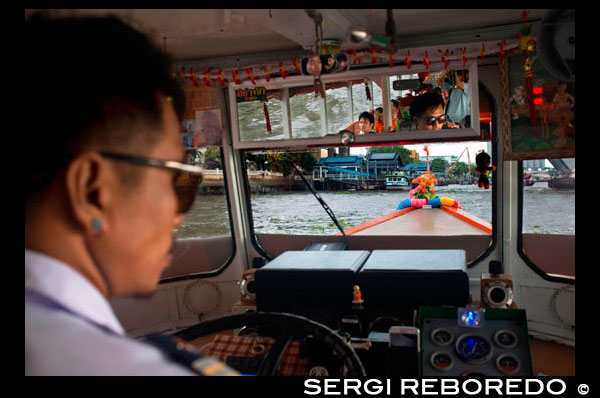 Chao Praya Express Boat driver. Bangkok, Inside public boat, ferry. Bangkok. Asia.  The Chao Phraya river makes a great way to get around, since many of the major tourist sites are easily accessible from the river. Chao Praya River Express operates a regular boat service up and down the river. Sort of a bus on the water. Fares are extremely cheap - you can get just about anywhere for 11 Baht to 25 Baht (0.34 USD to 0.76 USD) depending on the distance and the type of boat. There are piers next to many of the riverside hotels. Even if you aren't staying on the river, if you are staying close to the elevated train system, you can catch a train to the Taksin Bridge station. A River Express pier is on the river right below the station, and there is generally someone on duty at the pier to sell you a ticket and help plan your trip. The boats can be dangerously crowded during peak traffic times, so avoid rush hours.. Chao Phraya Pier Guide. Bangkok Waterways. Interesting piers found along the 21km Chao Phraya River Express Boat route. Temples, a wet market or an unexpected enclave... if it's something worth seeing then it's here. Once you've decided which piers you want to visit, use the quick links below to familiarise yourself with the different ferry lines, namely their routes, schedules and fares. Then set off on your custom-made - and dirt cheap - adventure on the River of Kings. A quick tip: of the five lines that ply the water the Orange Flag is your best bet - it operates all day. After the morning rush-hour, boats come every 20 minutes until around 16:00 when other lines kick into action and boats appear more frequently. If completely confused by the melee, another more comfortable option is a 'Tourist Boat', though these only come every 30 minutes. Operating Hours: 06:00 - 19:30 Price: Typically between 10 to 15 baht, though long journeys at peak hours can reach 30 baht (fares paid onboard).