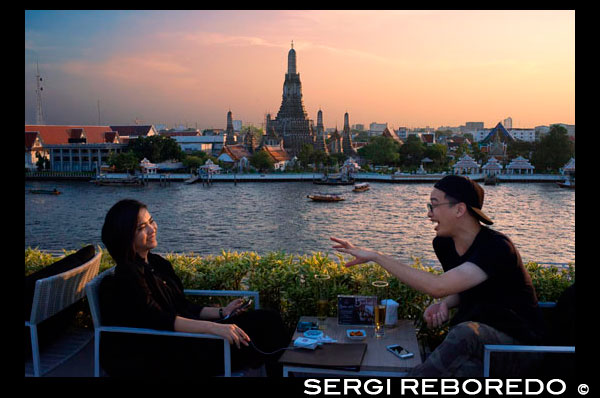 Pareja de amantes. Paisaje en la puesta del sol del templo de Wat Arun de Chao Praya río desde el techo de la Sala Rattanakosin hotel. Bangkok. Tailandia. Asia. Restaurante y bar Sala Rattanakosin, restaurante sala de Rattanakosin, es una opción de comedor frente al río escénico, con vistas al legendario río Chao Phraya y el templo místico de la madrugada. Sala Rattanakosin bangkok también cuenta con el techo, este bar de la azotea y terraza en Bangkok ofrece ajuste de la orilla del río idílico para relajarse con una bebida fría al final de un día maravilloso turismo. En Sala Rattanakosin, nos aseguramos de que los clientes tengan una experiencia inolvidable, ya que disfrutar de nuestro bar de vinos y restaurante en Bangkok. EL TECHO. elegante bar al aire libre en la azotea y un salón, con impresionantes vistas al río Chao Phraya, el templo del amanecer (Wat Arun) y otros sitios históricos. sirviendo cerveza, cócteles, vinos y aperitivos diarios. Un pintoresco, restaurante frente al río, con vistas al río Chao Phraya y el templo del amanecer (Wat Arun). el restaurante de dos plantas y dispone de asientos en el interior y un exterior más de comedor cubierta de agua, que sirve una variedad de platos internacionales deliciosos y una variada selección de platos tailandeses tradicionales. la barra del río cuenta con una variedad de vinos mundanos, cervezas y cócteles, y se ha convertido en una de las experiencias gastronómicas y románticas emblemáticos de bangkok.