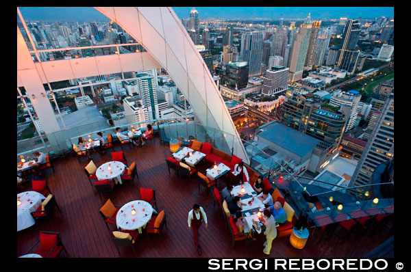 Red Sky Restaurant azotea. Bangkok. Tailandia. En la planta superior del Centara Grand rascacielos en el centro de la ciudad. La vista Chinatown, más el Gran Palacio y templos de la isla de Rattanakosin. Red Sky es uno de los nuevos bares de la azotea y restaurante en Bangkok. Si bien no ofrece golpear la orilla del río o vistas copas de los árboles que otros bares de la azotea gozan, tiene bastante impresionantes vistas panorámicas de 360 ??grados de su piso 55, uno de los lugares más convenientes de la ciudad. Si usted visita Bangkok, es probable que el resultado final será ir de compras en la zona de Siam, donde se encuentran los más grandes y modernos centros comerciales, como el legendario Siam Paragon, MBK y el CentralWorld recién reconstruido. Red Sky bar es parte del Centara Grand Hotel, que en sí es en realidad parte de este gigantesco centro comercial Central World. Por lo que parece ser una combinación perfecta: tienda hasta sus gotas de tarjetas de crédito, luego de recuperarse de kilómetros y kilómetros de caminar con una cena o una copa de vino con vistas inolvidables de la azotea por encima del propio centro comercial.