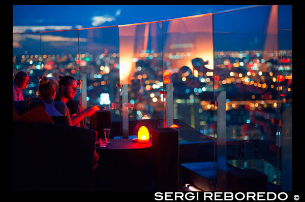 Red Sky Restaurant Rooftop. Bangkok. Thailand. On the top floor of the Centara Grand skyscraper in the city centre. The view  Chinatown, plus the Grand Palace and temples of Rattanakosin Island. Red Sky is one of the newest rooftop bars and restaurant in Bangkok. While it doesn't offer striking riverside or treetop views that other rooftop bars enjoy, it has pretty impressive 360-degree panoramic vistas from its 55th floor, one of the most convenient locations in town. If you visit Bangkok, chances are you will end up shopping in the Siam area, where the largest and most trendy shopping malls are located, such as the legendary Siam Paragon, MBK and the newly rebuilt CentralWorld. Red Sky bar is part of the Centara Grand Hotel, which itself is actually part of this gigantic CentralWorld shopping mall. So it seems to be a perfect combination: shop till your credit card drops, then recover from walking miles and miles with a dinner or a glass of chilled wine with unforgettable views from the rooftop above the shopping mall itself.