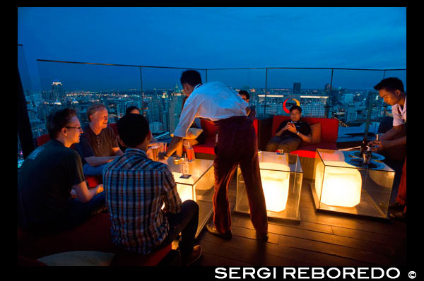 Red Sky Restaurant azotea. Bangkok. Tailandia. En la planta superior del Centara Grand rascacielos en el centro de la ciudad. La vista Chinatown, más el Gran Palacio y templos de la isla de Rattanakosin. Red Sky es uno de los nuevos bares de la azotea y restaurante en Bangkok. Si bien no ofrece golpear la orilla del río o vistas copas de los árboles que otros bares de la azotea gozan, tiene bastante impresionantes vistas panorámicas de 360 ??grados de su piso 55, uno de los lugares más convenientes de la ciudad. Si usted visita Bangkok, es probable que el resultado final será ir de compras en la zona de Siam, donde se encuentran los más grandes y modernos centros comerciales, como el legendario Siam Paragon, MBK y el CentralWorld recién reconstruido. Red Sky bar es parte del Centara Grand Hotel, que en sí es en realidad parte de este gigantesco centro comercial Central World. Por lo que parece ser una combinación perfecta: tienda hasta sus gotas de tarjetas de crédito, luego de recuperarse de kilómetros y kilómetros de caminar con una cena o una copa de vino con vistas inolvidables de la azotea por encima del propio centro comercial.