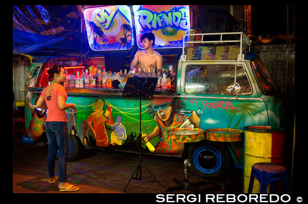 Un bar de cócteles autobús VW de Volkswagen en Soi Rambuttri. Bangkok. Tomar una cerveza con hielo o un cóctel en uno de los bares de pop-up y tire hacia arriba de un asiento con los lugareños. El mejor lugar para probar es a lo largo de la parte posterior del templo donde se puede escuchar buena música en vivo y un ambiente acogedor y alegre. Estos lugares no suelen ponerse a trabajar hasta después de las 23:00 sin embargo. También puede encontrar un par de los bares increíbles coches decorados en Rambuttri - una caravana VW y un songtaew. VW bares son furgonetas convertidas con el personal que operan las cocteleras desde el interior del Volkswagen. Decorado con luces de neón, bolas de discoteca e impresionantes sistemas de sonido a todo volumen de los últimos éxitos del pop, son una adición notable a la fiesta en la calle Sukhumvit 11 Bangkok es una ciudad donde sólo se puede encontrar tan fácilmente potable de alta gama y de comedor, usted puede baratísimo, abajo y hacia afuera alcohol y comilona, ??y Sukhumvit Soi 11 es uno de esos raros sois que muestra clubes y bares para todos los presupuestos. La regla general es que cuanto más se aventura hasta el soi, el más caro las opciones de conseguir. Sin embargo, las barras de VW, salpicadas a lo largo de toda la calle, son casi tan barato como se pone, y le permiten lubricar, bajo la mirada de la cama muy caros Supper Club, sin poner siquiera una grieta en su billetera.