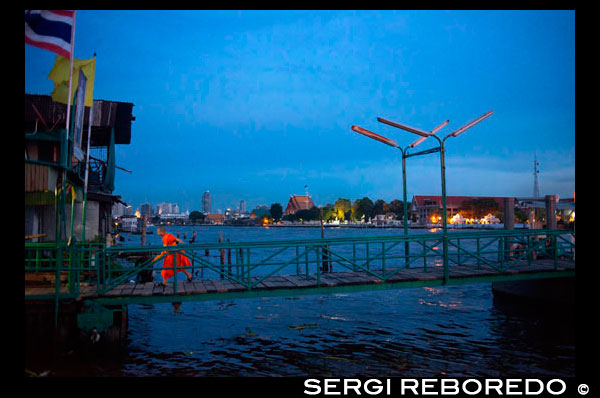 Monjo jove en Chao Praya exprés parada de vaixell. Bangkok, vaixell Pública, ferri. Bangkok. Àsia. El riu Chao Phraya fa una gran manera de moure, ja que molts dels principals llocs d'interès turístic són fàcilment accessibles des del riu. Chao Praya River Express opera un servei regular de vaixell de dalt i baix del riu. Ordenar d'un autobús a l'aigua. Els preus són molt barats - es pot arribar a qualsevol lloc per a 11 baht a 25 baht (0,34 $ a 0,76 dòlars), depenent de la distància i el tipus de vaixell. Hi ha molls al costat de molts dels hotels de ribera. Fins i tot si no t'allotges al riu, si et quedaràs a prop del sistema de tren elevat, pot agafar un tren a l'estació de Pont de Taksin. Una molla de River Express es troba en el riu just a sota de l'estació, i en general hi ha algú de guàrdia al moll de vendre una butlleta i ajudar a planificar el seu viatge. Els vaixells poden ser perillosament ple de gent durant les hores punta de trànsit, de manera que evitar les hores punta .. Guia Pier Chao Phraya. Vies navegables Bangkok. Embarcadors interessants que es troben al llarg de la ruta Chao Phraya River Express Boat 21 quilòmetres. Temples, un mercat mullat o un enclavament inesperat ... si és una cosa digna de veure, llavors és aquí. Una vegada que hagis decidit quin molls que desitja visitar, utilitzeu els enllaços a continuació per familiaritzar-se amb les diferents línies de ferri, és a dir, les seves rutes, horaris i tarifes. Després va partir en la seva mesura - l'aventura en el Riu dels Reis - i molt barat. Un consell ràpid: de les cinc línies que solquen l'aigua amb la Bandera Taronja és la seva millor aposta - que funciona tot el dia. Després del matí hora punta, vaixells vénen cada 20 minuts fins al voltant 16:00 quan altres línies puntada en acció i vaixells apareixen amb més freqüència. Si completament confós pel cos a cos, una altra opció més còmoda és un "vaixell turístic ', encara que aquests només vénen cada 30 minuts. Hores de funcionament: 6: 00-19: 30 Preu: Normalment entre 10 a 15 Baht, encara que llargs viatges en hores punta pot arribar a 30 baht (tarifes pagades a bord).