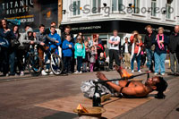 A juggler tries to pass under the fire in Arthur Square. Arthur Square is also known as Cornmarket (It was previously known as The Shambles). This area in the heart of Belfast has been linked to commerce since at least 1604. Sir Arthur Chichester, the Lord Deputy of Ireland in that year, received a grant of this town, which along with the Manor and Castle included permission to hold fairs and Markets. Arthur wasted no time in developing the small settlement into a profitable centre of commerce. The first Belfast Fair was held on 1st August 1604. By encouraged traders and craftsmen to move here with their families, the area developed, and regular markets were held. A Market House was built at the corner of Cornmarket and High Street (it was demolished in 1811, having stood for 200 years). This is also known in local history as the place where, on 17th July 1798, Henry Joy Mc Cracken was tried and found guilty of treason. He was hung in this square the same day. 